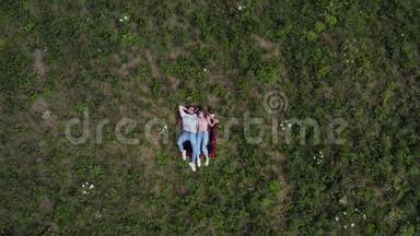 幸福的年轻夫妇躺在草地上。 摄像机慢慢地从他们身边<strong>飞走了</strong>。 从高空向下。 4K.